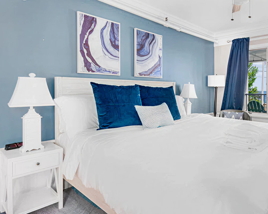 Boutique hotel bedroom with blue walls, crisp white bedding, and navy accent pillows