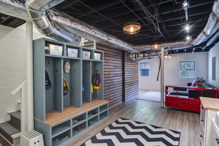 A basement with storage cubbies a black and white chevron area rug and a storage cart