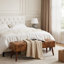 Brown faux leather tufted bench with dark brown wooden legs placed at the foot of a bed.