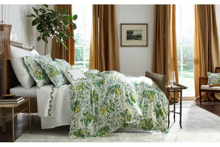 large bed with green sham and floral linens and bedding