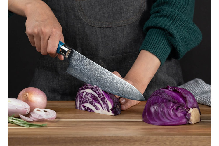 a person using a chef's knife to slice cabbage