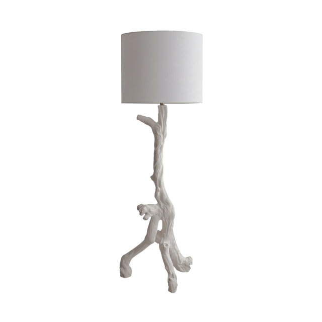 White floor lamp featuring a base sculpted like a piece of driftwood topped with a cylindrical fabric drum shade.