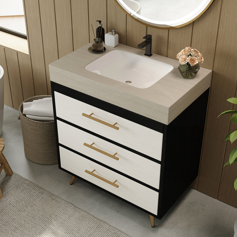 Meuble-lavabo sur pied contemporain avec lavabo en céramique intégré et surface en pierre frittée. Ce meuble-lavabo offre un support stable avec ses pieds en acier thermolaqué et ses poignées encastrées dorées. L'évier a un grand