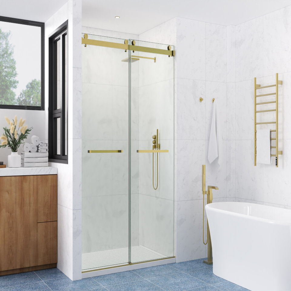Frameless sliding shower door with brushed gold hardware in a modern white marble bathroom with a freestanding tub and wall-mounted towel warmer.