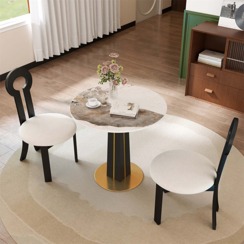 Table ronde moderne avec un plateau en pierre frittée de 85 cm, des pieds en bois noir et un support en métal doré, idéal pour les discussions de salle à manger sur une base en bois blanc, un choix pratique