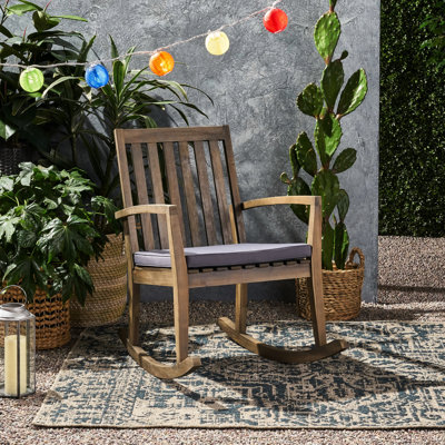Chaise berçante en bois avec coussin gris foncé pour une détente en plein air