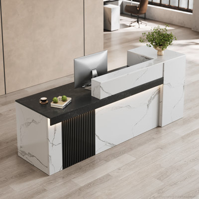 Bureau d'accueil moderne en forme de L, aspect marbre blanc, avec éclairage DEL chaleureux, prises électriques intégrées, ports USB, système de gestion des câbles et rangement pour dossiers.