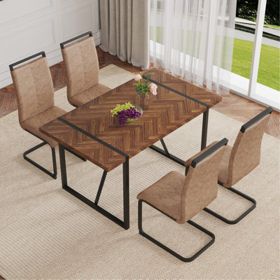 Ensemble de table et de chaises. Une table de salle à manger rectangulaire rétro avec un bureau en panneau de fibres à densité moyenne à motif en arête de poisson et des pieds en métal noir. Assorti de 4 chaises en tissu brun avec des pieds arqués noirs.