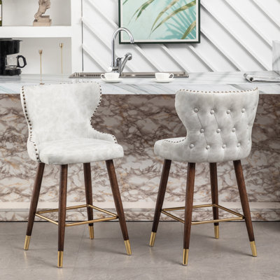 2 tabourets de comptoir modernes à 2 compartiments Mid-Century - Similicuir, avec garniture cloutée, siège incurvé, pieds fuselés en noyer, repose-pieds en métal Siège rembourré en cuir. Bois massif doré