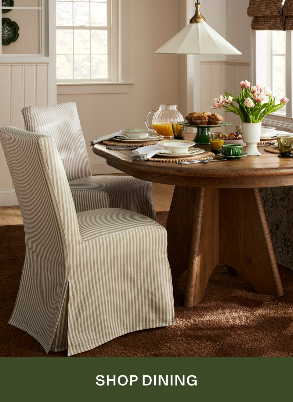 Striped skirted dining chairs at a round wooden table set for brunch with tulips and muffins, SHOP DINING
