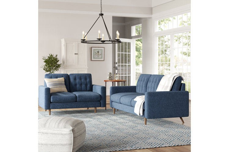 Neutral white living room with two blue sofas and a wagon wheel chandelier.