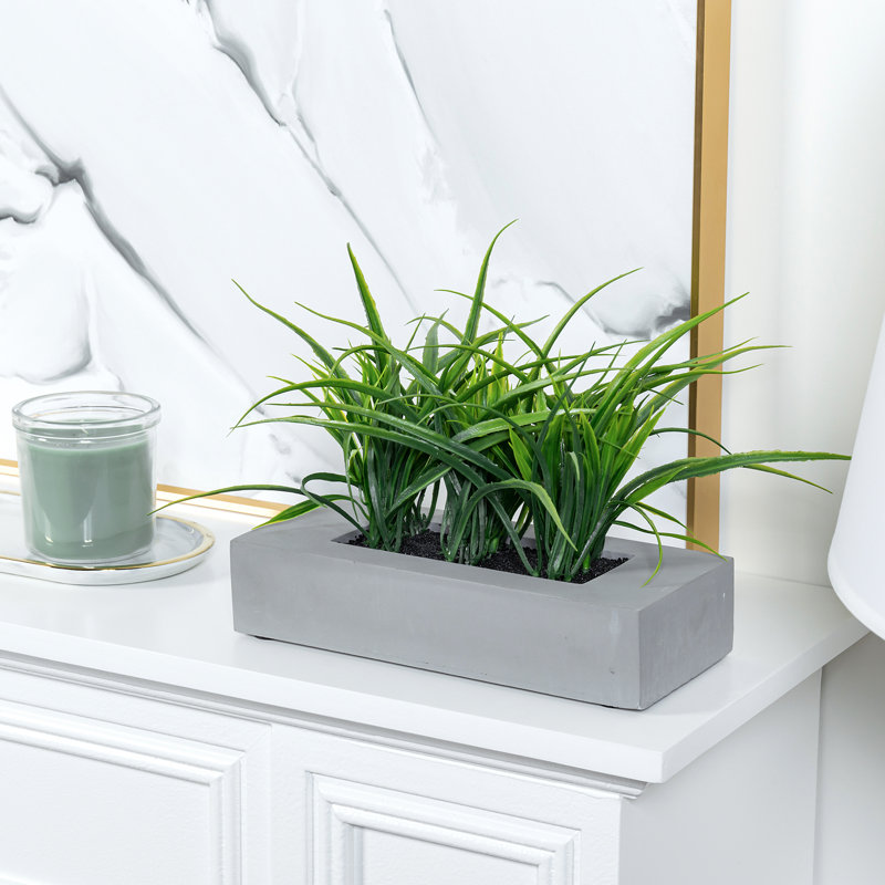 Faux herbes vertes dans une boîte en béton gris