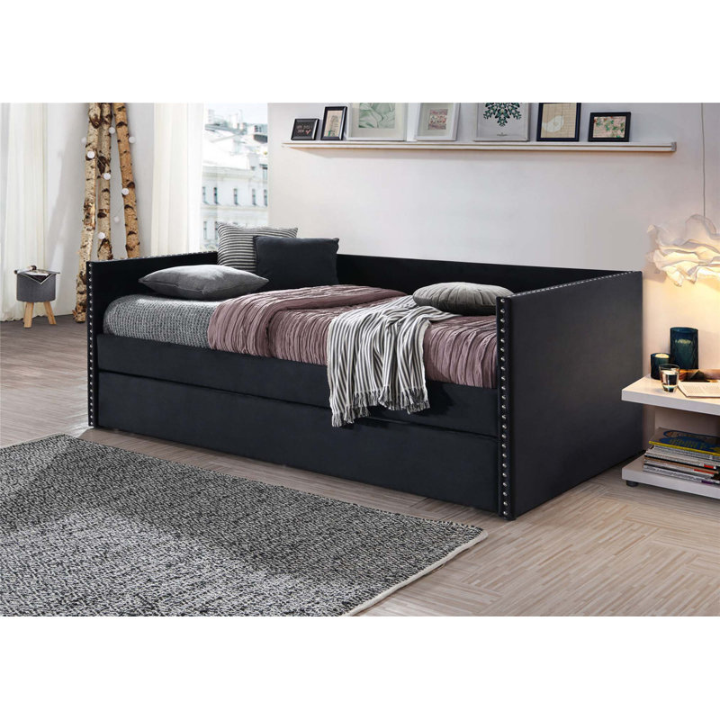 Lit de jour moderne capitonné avec couchette coulissante et garniture cloutée pour des solutions de couchage et de sièges polyvalentes.