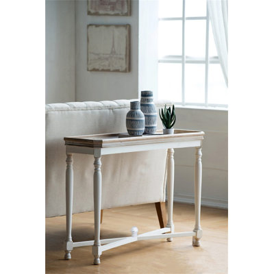 La console étroite Alcott, parfaite pour les petits espaces avec des pieds blancs antiques et un plateau naturel, est idéale pour les vestibules ou derrière les canapés.