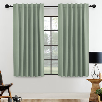 Set of two sage green thermal curtain panels hanging on a black curtain rod.