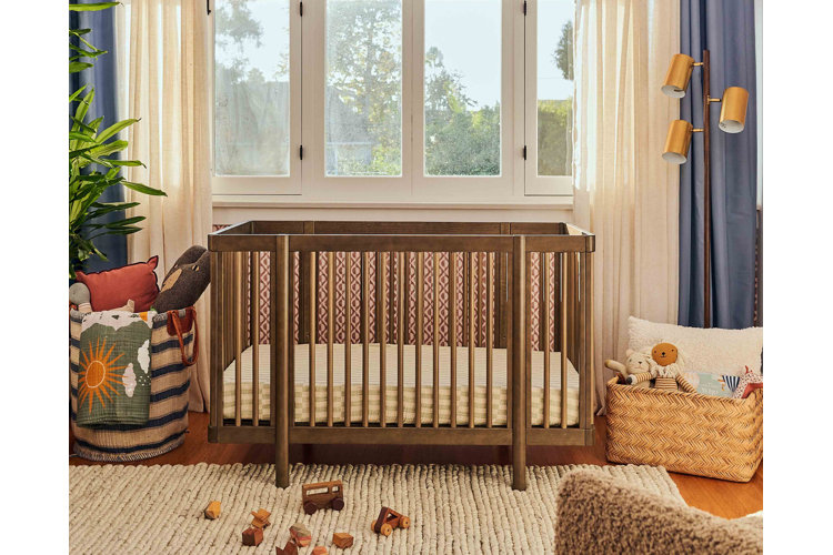 beautiful wood crib with yellow sheet. two woven baskets filled with stuffed toys and bedding. woven rug with wood toys on it