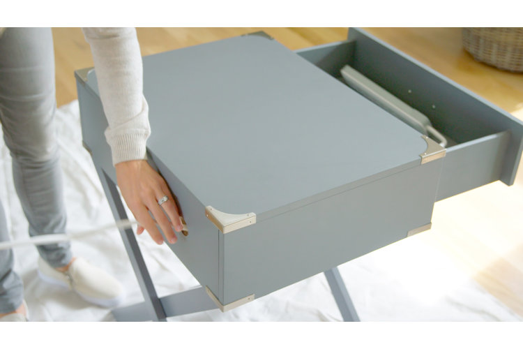 Person threading a power strip's cord through the back of the nightstand through the newly drilled hole.