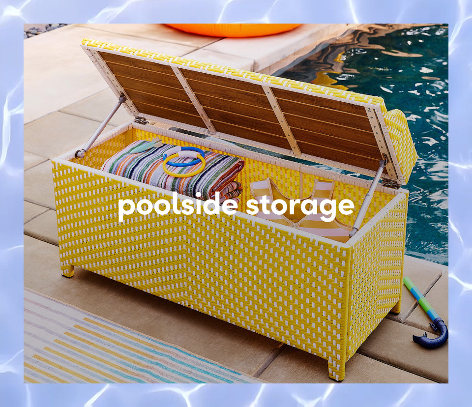 A yellow and white woven outdoor storage bench with an open lid, filled with pool towels and colorful rings.