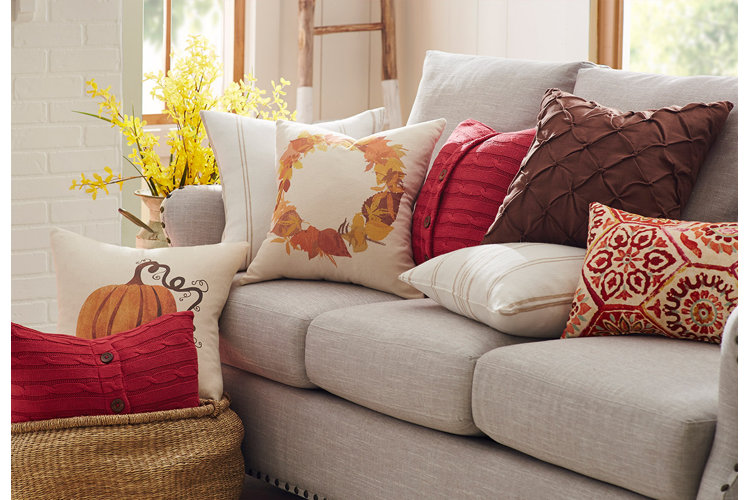 gray upholstered sofa with red, orange, and cream throw pillows