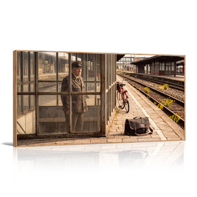 Man in Vintage Uniform at Rustic Train Station with Bicycle Canvas Wall Art