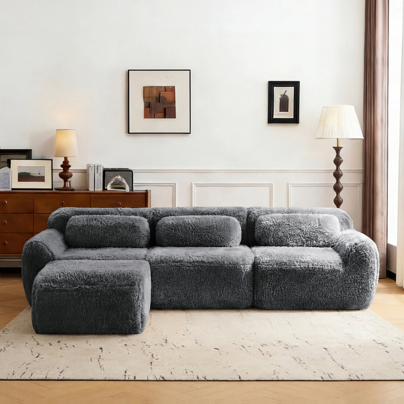 Canapé modulaire en L en peluche avec zones compressées, rembourré de mousse haute densité 32D, comprenant un repose-pieds amovible.