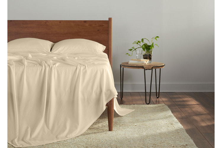Soft champagne linen bed sheets with smooth drape on wooden bed, showcasing breathable, lightweight bedding in a minimalist bedroom