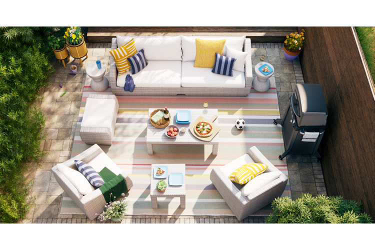 backyard patio with a white wicker patio set, striped outdoor rug, and a grill