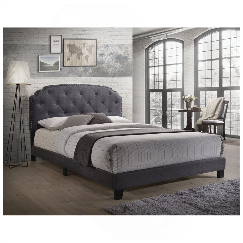 Grand lit tapissier gris avec garniture cloutée et tête de lit arquée, parfait pour les chambres contemporaines et élégantes.