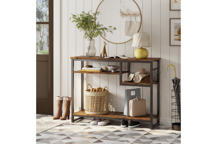a wood console table next to a front door with a yellow lamp, plant, storage basket, and decor
