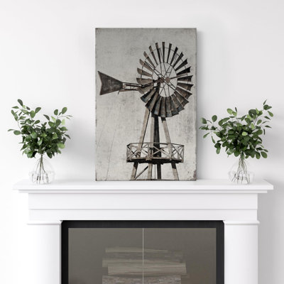 Canvas wall art featuring a rustic windmill in gray tones, displayed on a fireplace mantel.