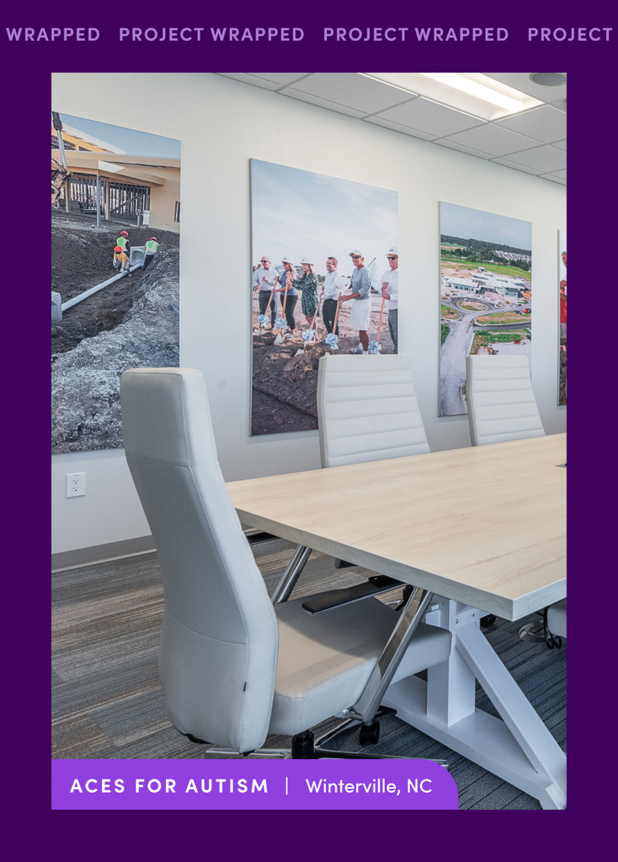 Project Wrapped office featuring a conference table, chairs, and construction photos on the wall. ACES for Autism, Winterville, NC.