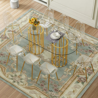 Ensemble de table et de chaises Table de salle à manger ovale en verre trempé de 71 pouces de style luxueux à double colonne dorée. Jumelé avec 8 chaises en plastique transparent avec des pieds en métal doré.