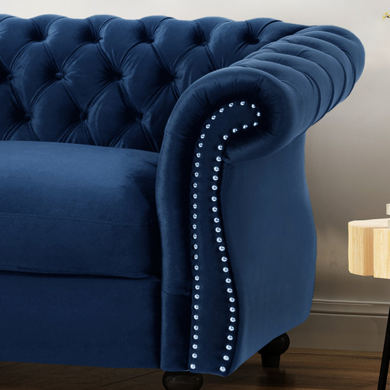 En velours bleu marine pour une assise relaxante, ornée de clous décoratifs et d'un rembourrage profond.