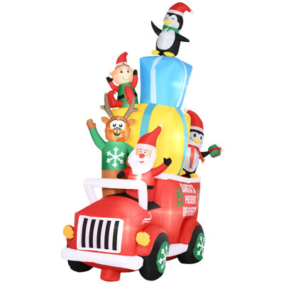 Le père Noël conduit une voiture-cadeau avec un wapiti, un elf et deux pingouins gonflables
