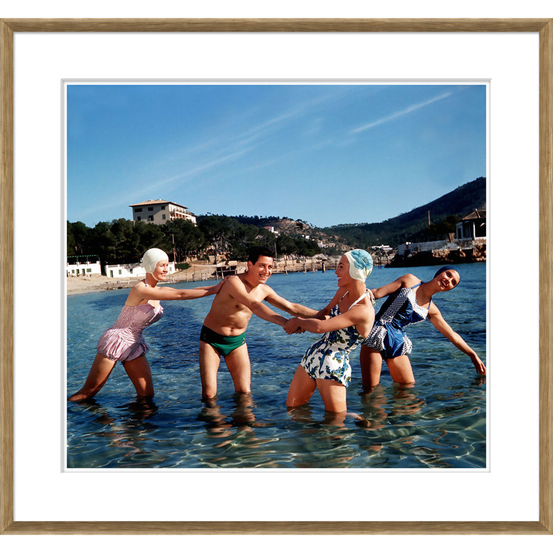 «Trois femmes heureuses et un homme jouant dans l'eau» par Getty Images - cadre photographique sur papier