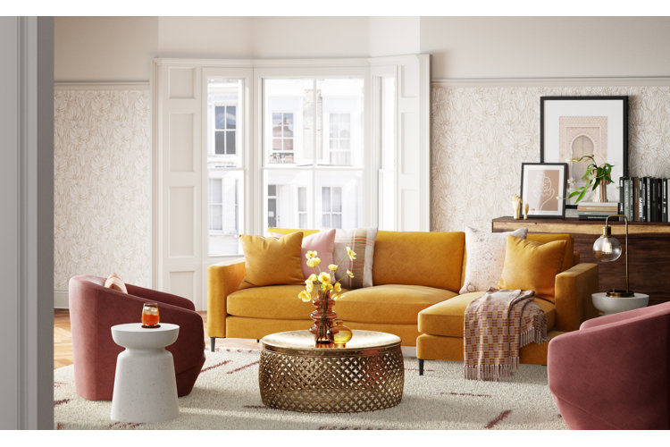 bright transitional living room with a marigold-colored sectional, two mauve accent chairs, and a round gold coffee table