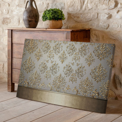 La toile crée un design de papier peint élégant avec un motif damassé complexe en or chatoyant contre un taupe doux