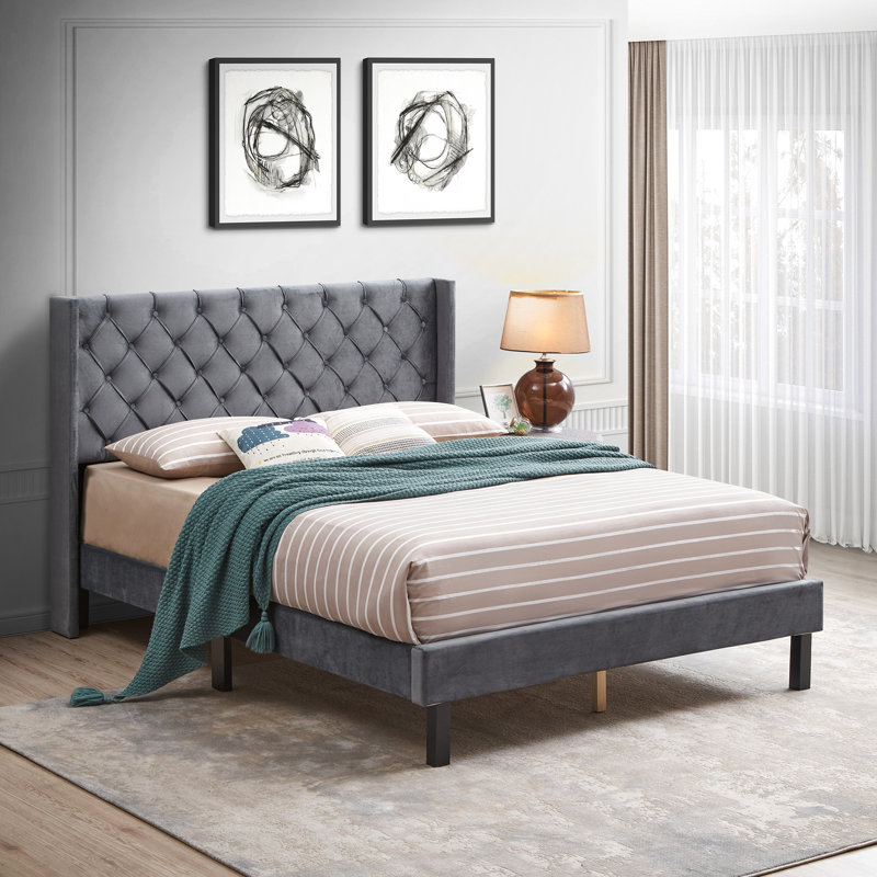 Grand lit plateforme avec revêtement en velours gris et structure ailée