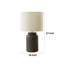 Lampe de table Rumi avec détails de grain, base en résine brune, abat-jour tambour ivoire-117054310