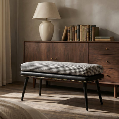 Banc rembourré à motif noir et blanc avec des détails cloutés au pied du lit et des pieds noirs effilés; un banc en similicuir adapté à la chambre à coucher ou au vestibule