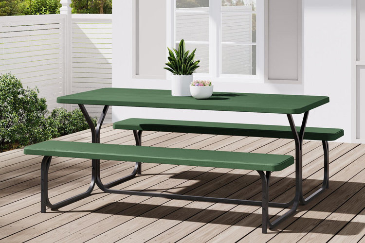 green picnic table with attached benches on a wooden deck, styled with potted plants