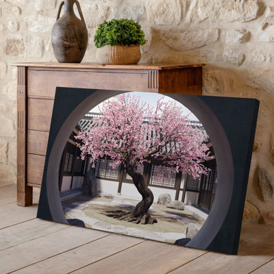 Toile, cour sereine et mystique avec un grand arbre de fleurs de cerisier encadré par une arche de pierre circulaire
