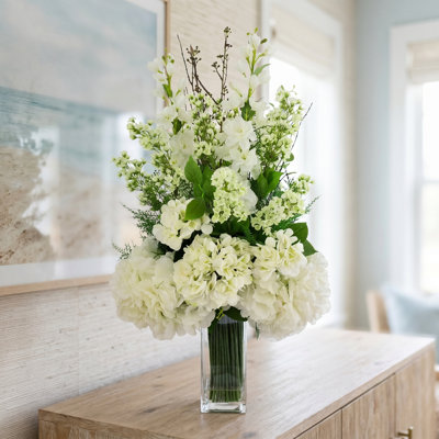 Arrangement floral Delphinium, hortensia et fougère dans un grand vase en verre