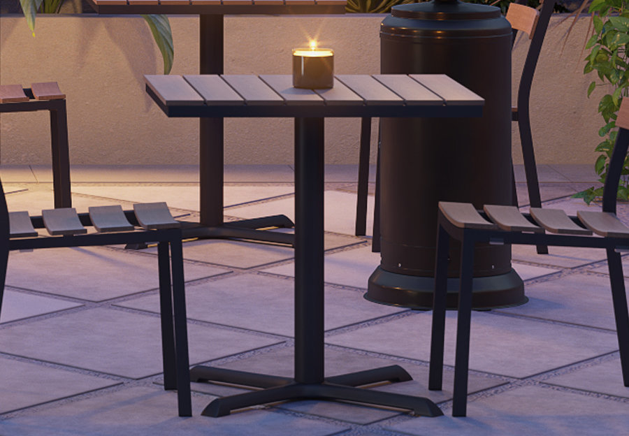 Metal restaurant table outside on a patio. There's a candle on top of the table.