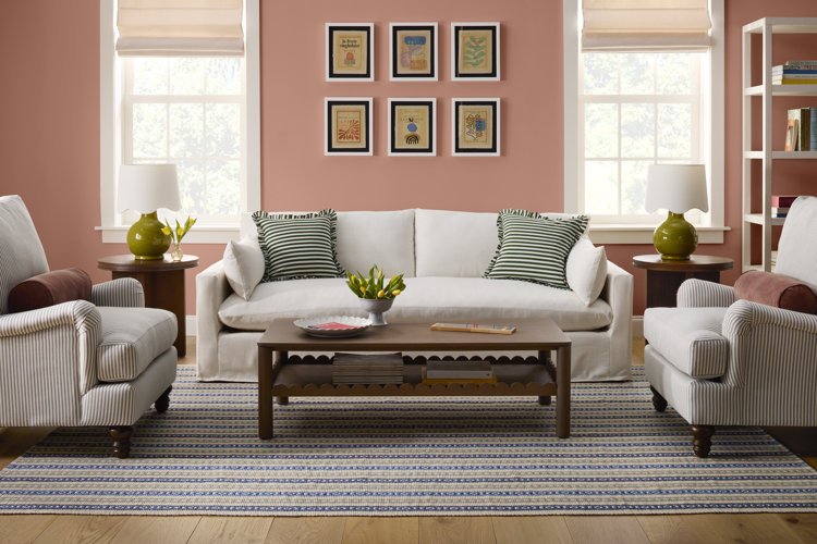 cottage style sitting room with salmon pink walls a white slipcover sofa striped accent chairs and striped pillows from cozy sitting room ideas