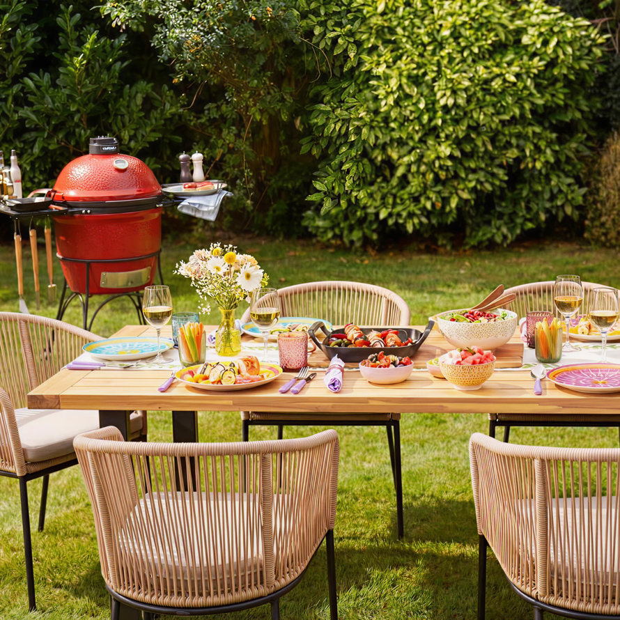 Outdoor dining set with table, chairs, cushions, and a blue patterned rug.