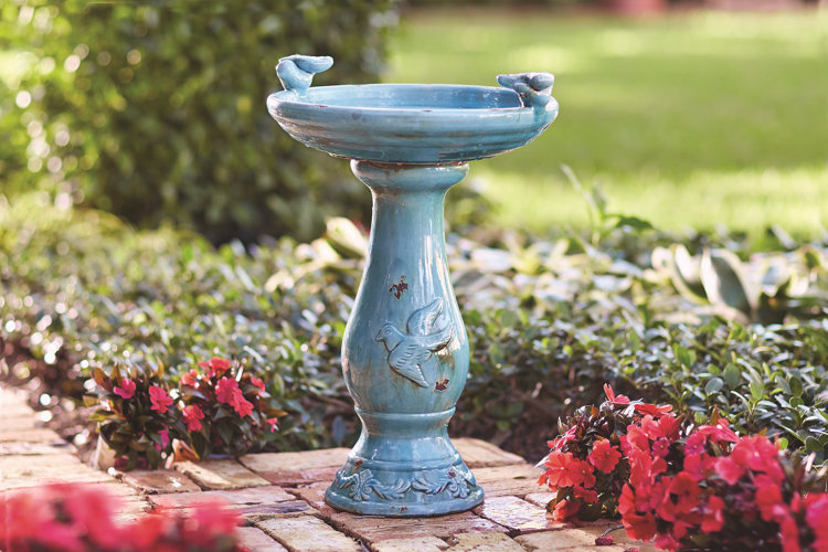 blue ceramic bird bath on a brick patio