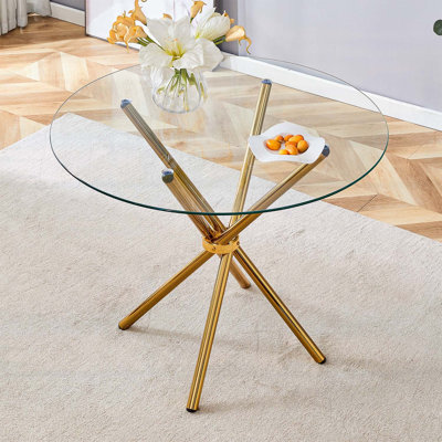Table de salle à manger ronde en verre transparent avec pieds uniques en forme d'anneau en métal doré pour 4 à 6 personnes, parfaite pour les intérieurs modernes et polyvalents.