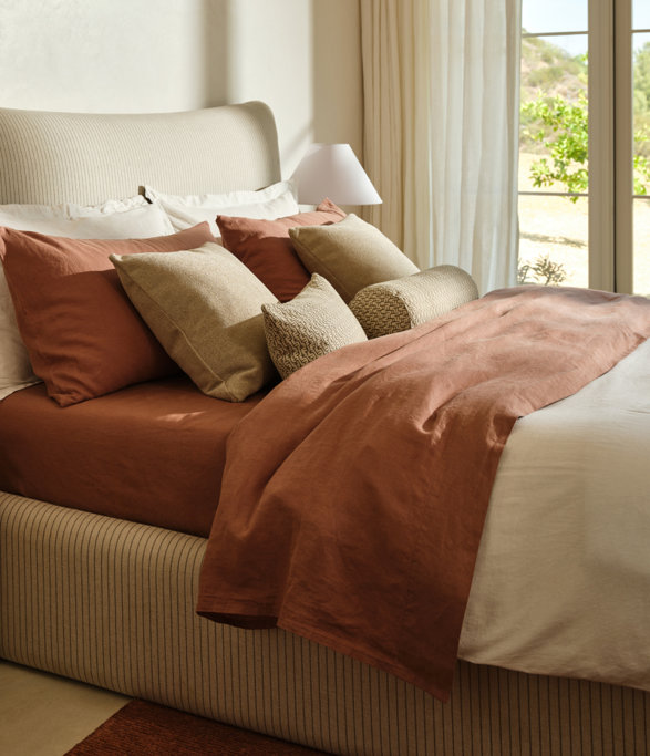 Bedroom with striped upholstered headboard and bed frame, and layered pillows and duvet.