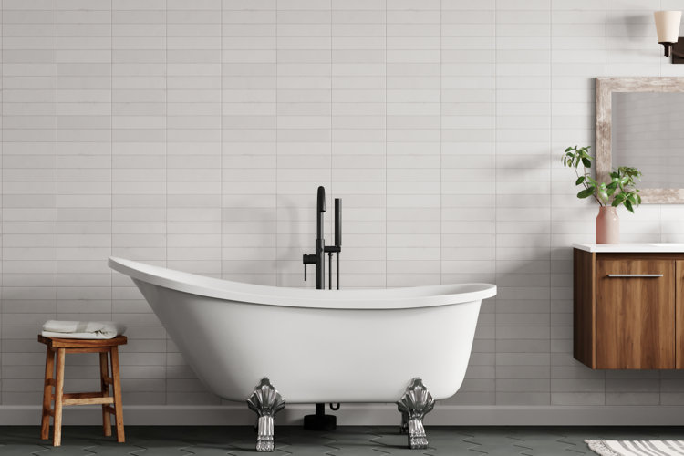 modern bathroom with pale gray tile, clawfoot bathtub, and a wood stool